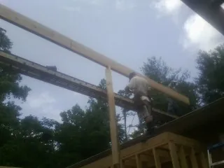 Carpenter setting a ridge beam over a new addition frame — Ice Dam Removal by Roofing Brothers in Osterville