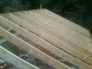 New roof rafters set over an addition before sheathing in Osterville