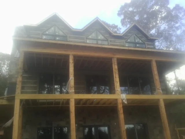 Dormers and porch framing on a large log home under construction — Roof Coating work by our crew in Osterville
