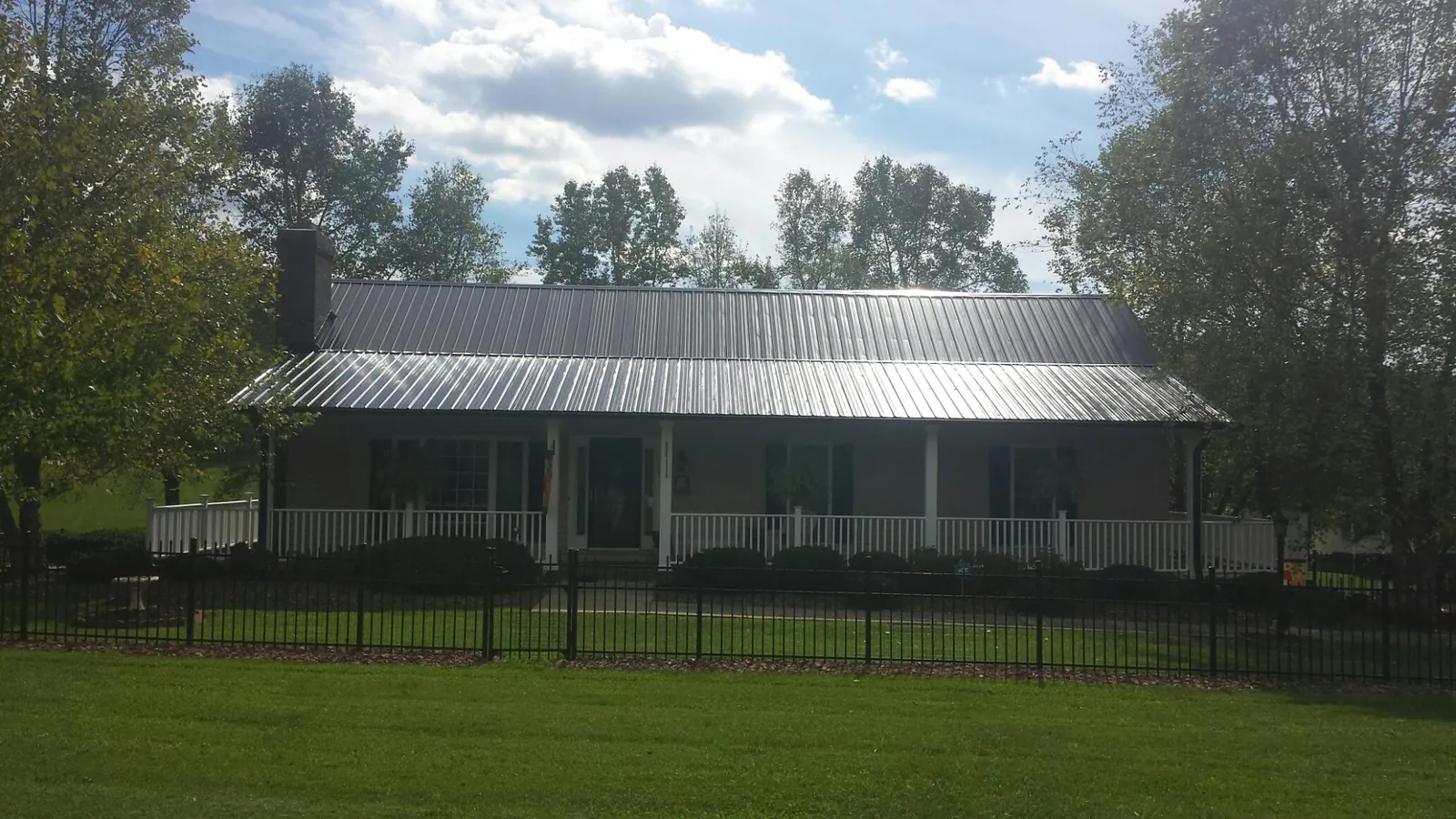 Gray metal roof on a brick ranch with a full width front porch — Gutter Guard Installation work by our crew in Osterville