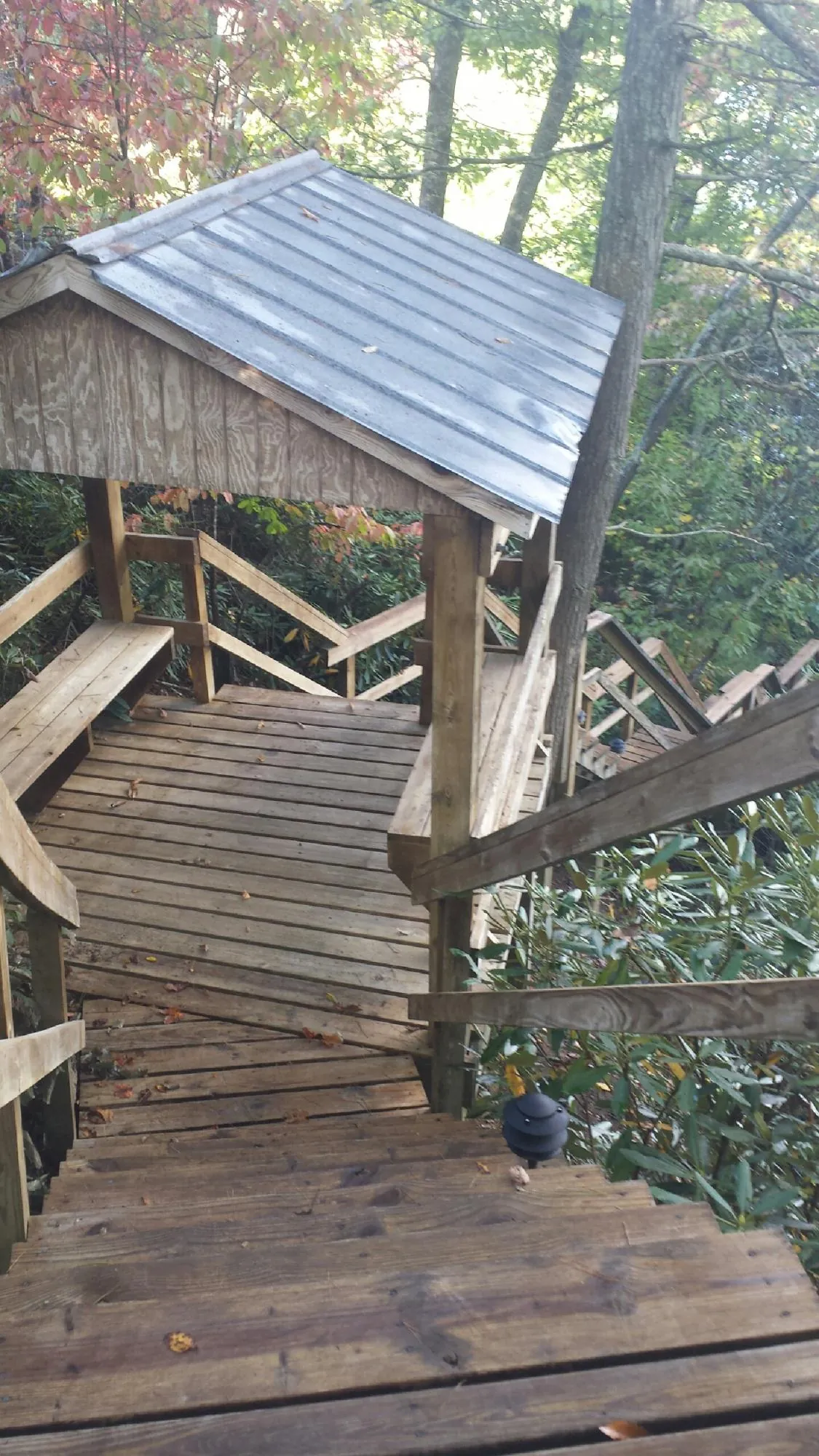 Metal roofed shelter over wooden steps on a wooded walkway — Skylight Repair & Installation work by our crew in Osterville